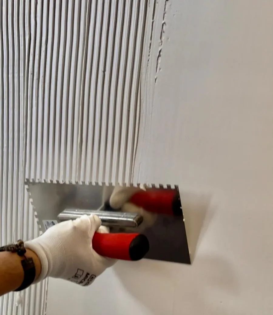 Die weiße Funktionsschicht wird mit einer Glättkelle auf eine Innenwand aufgezogen.